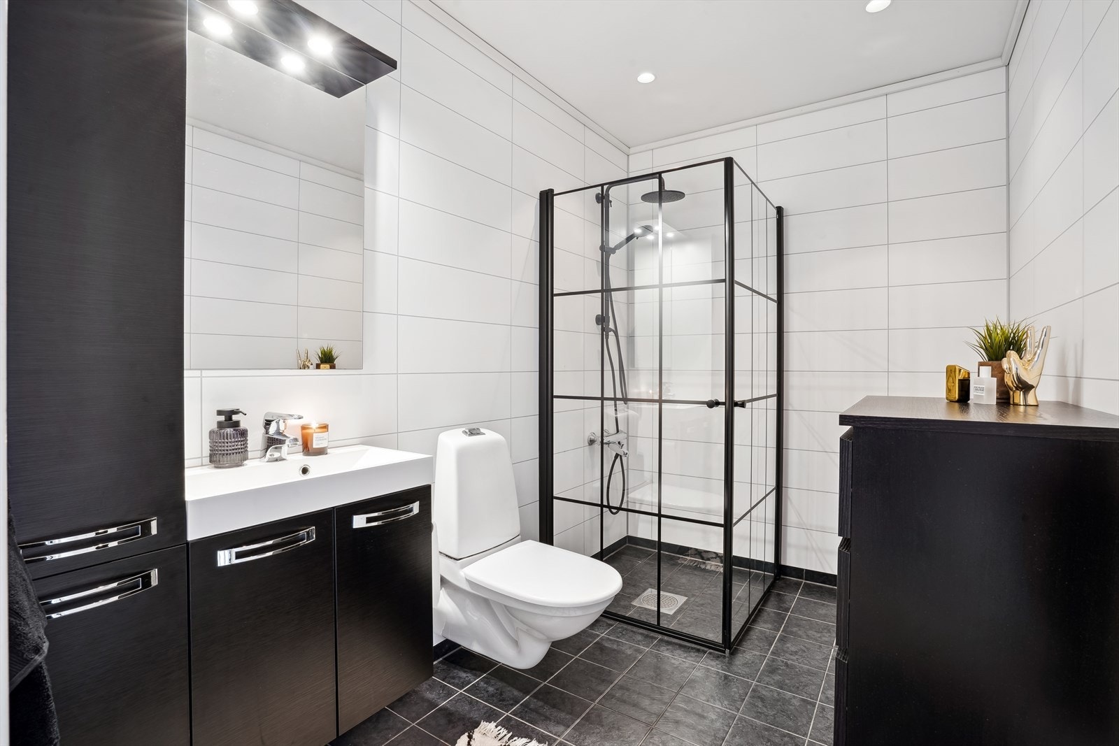 Delikat baderom med flislagt gulv og baderomsplater med flisprofil på veggene. Galleribilde