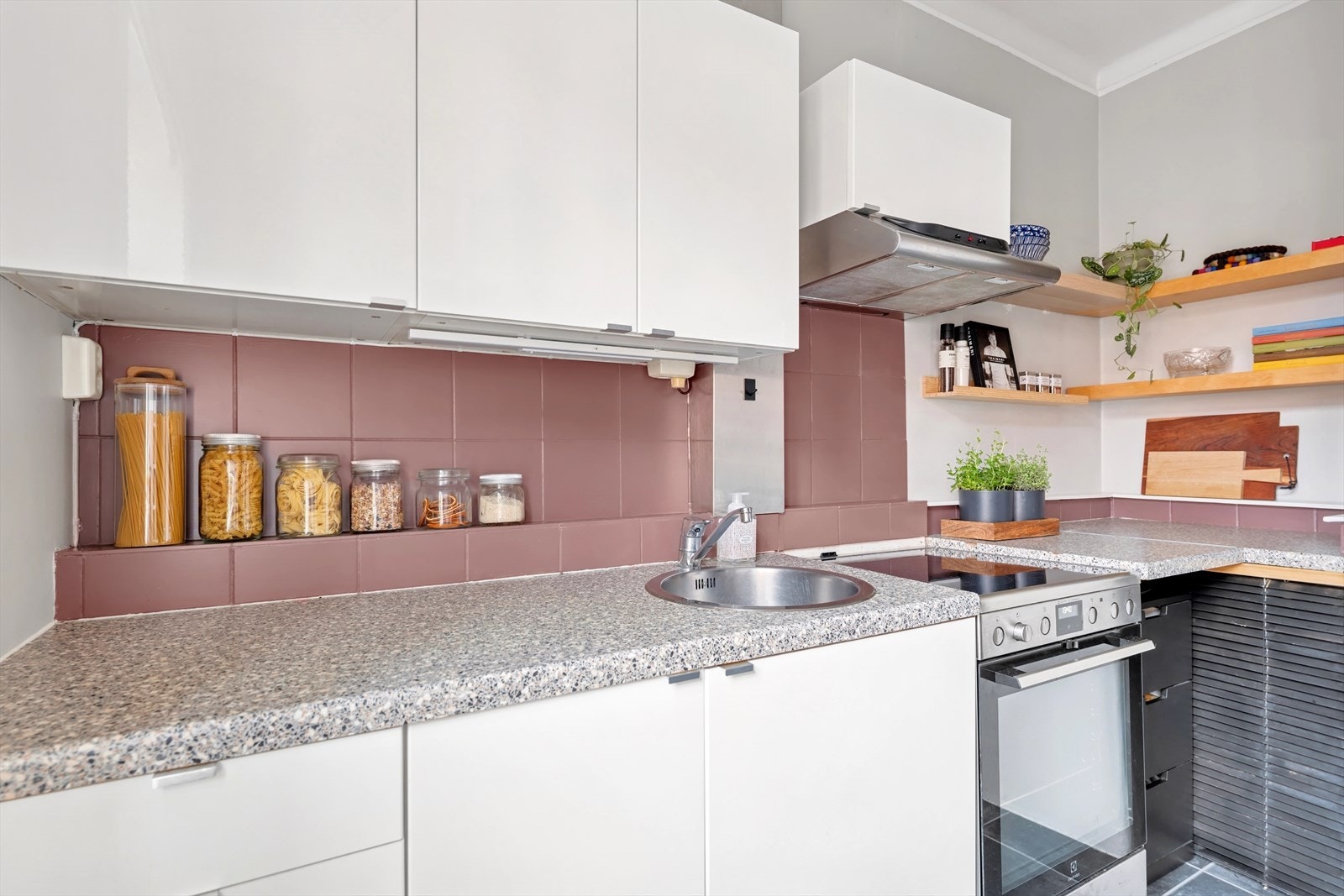 Glatt laminert kjøkkeninnredning, fliser mellom overskap og laminert benkeplate, lys under overskap Galleribilde