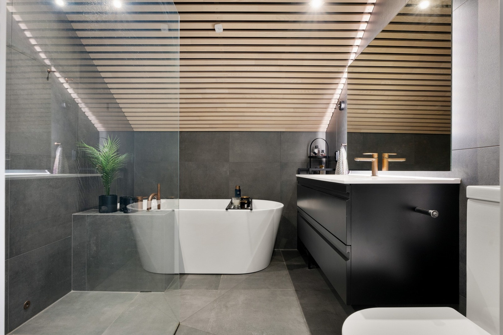 Fliser på gulv og vegger kombinert med stilrent spilepanel i taket gir badet et eksklusivt preg. Galleribilde