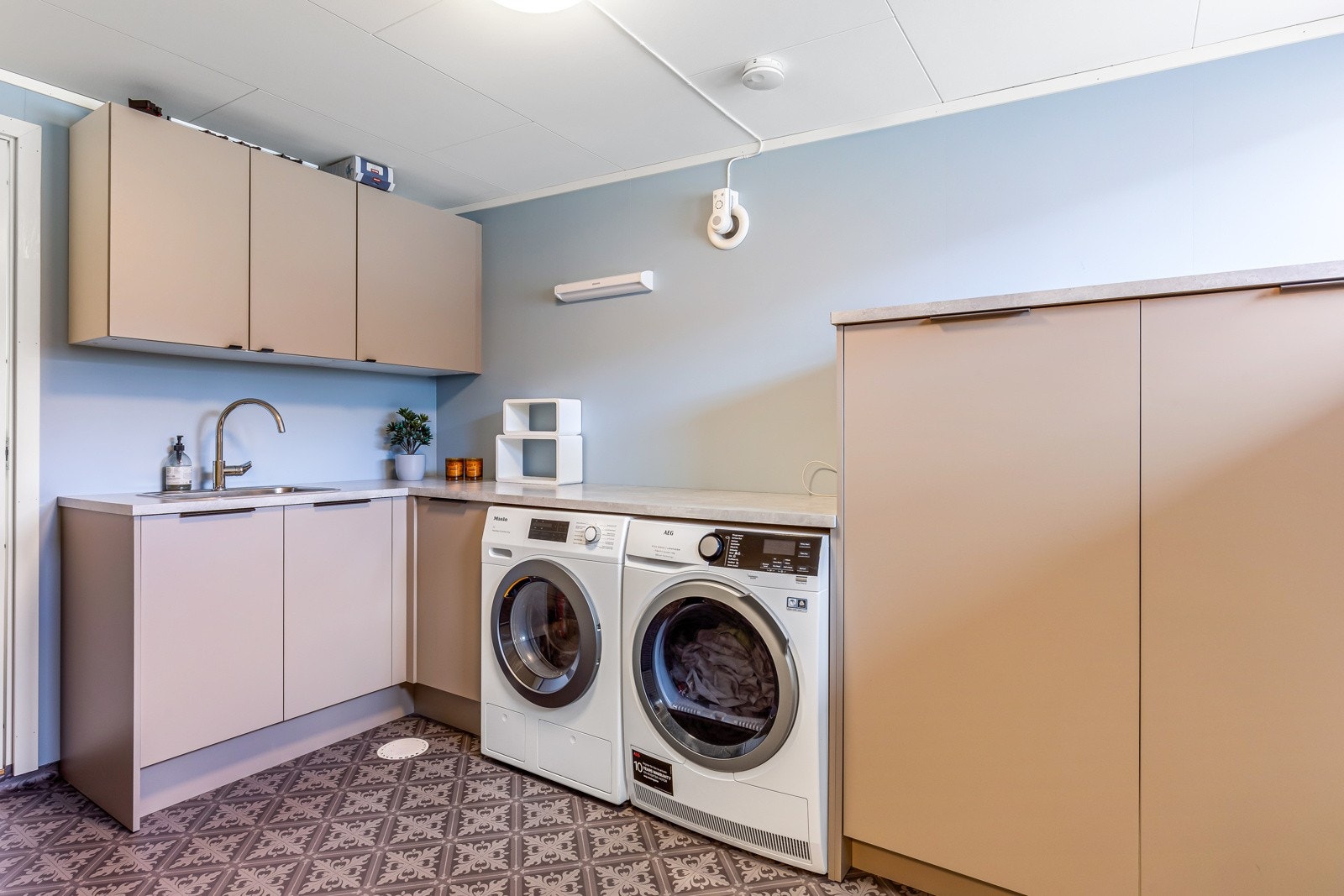 Praktisk vaskerom med vask, godt med skapplass og opplegg for vaskemaskin og tørketrommel Galleribilde