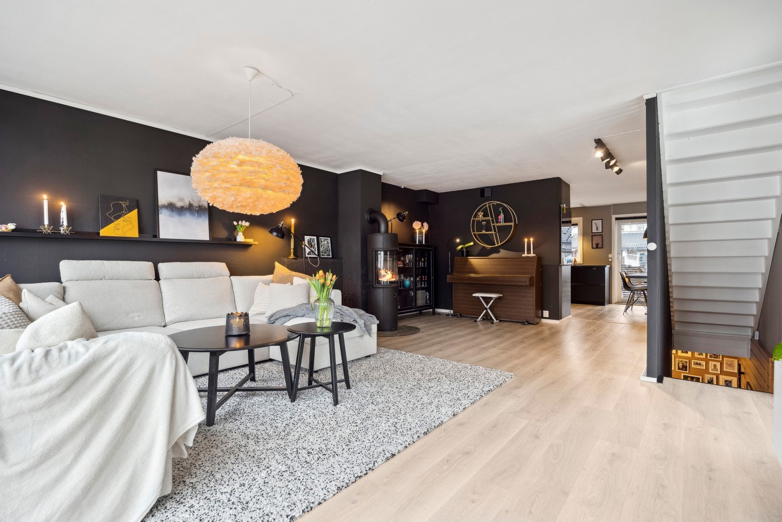 Nyt varme og hygge foran den stilrene peisen. Den mørke kontrastveggen gir rommet et elegant uttrykk, kombinert med lune tekstiler og harmoniske farger. Galleribilde