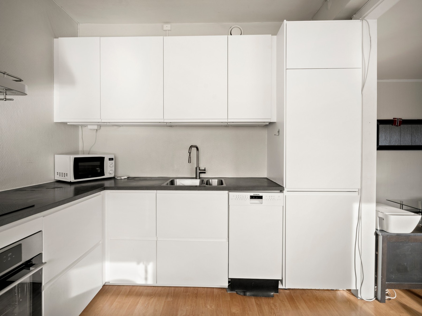 Integrerte hvitevarer bestående av stekeovn, nedfelt induksjonstopp, oppvaskmaskin og kjøl/frys. Galleribilde