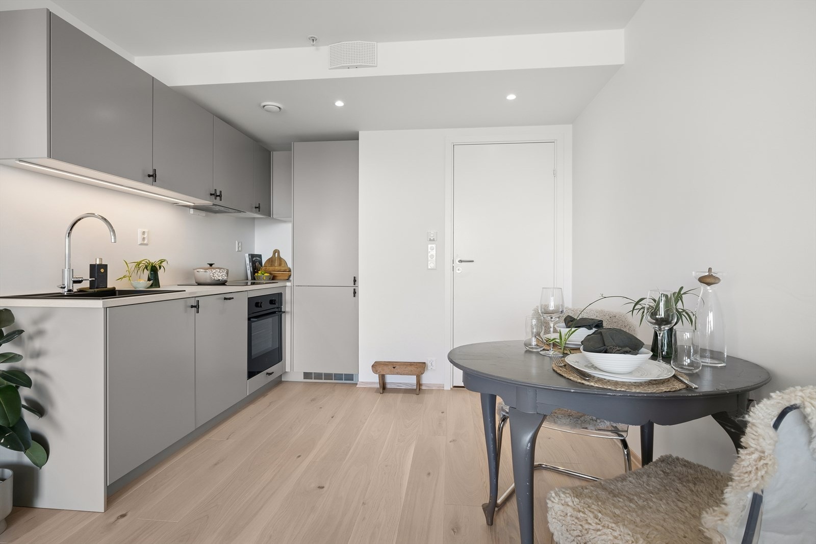 Her er det en stilfull kjøkkeninnredning utført med grå, glatte fronter og laminat benkeplate med en kum. Galleribilde