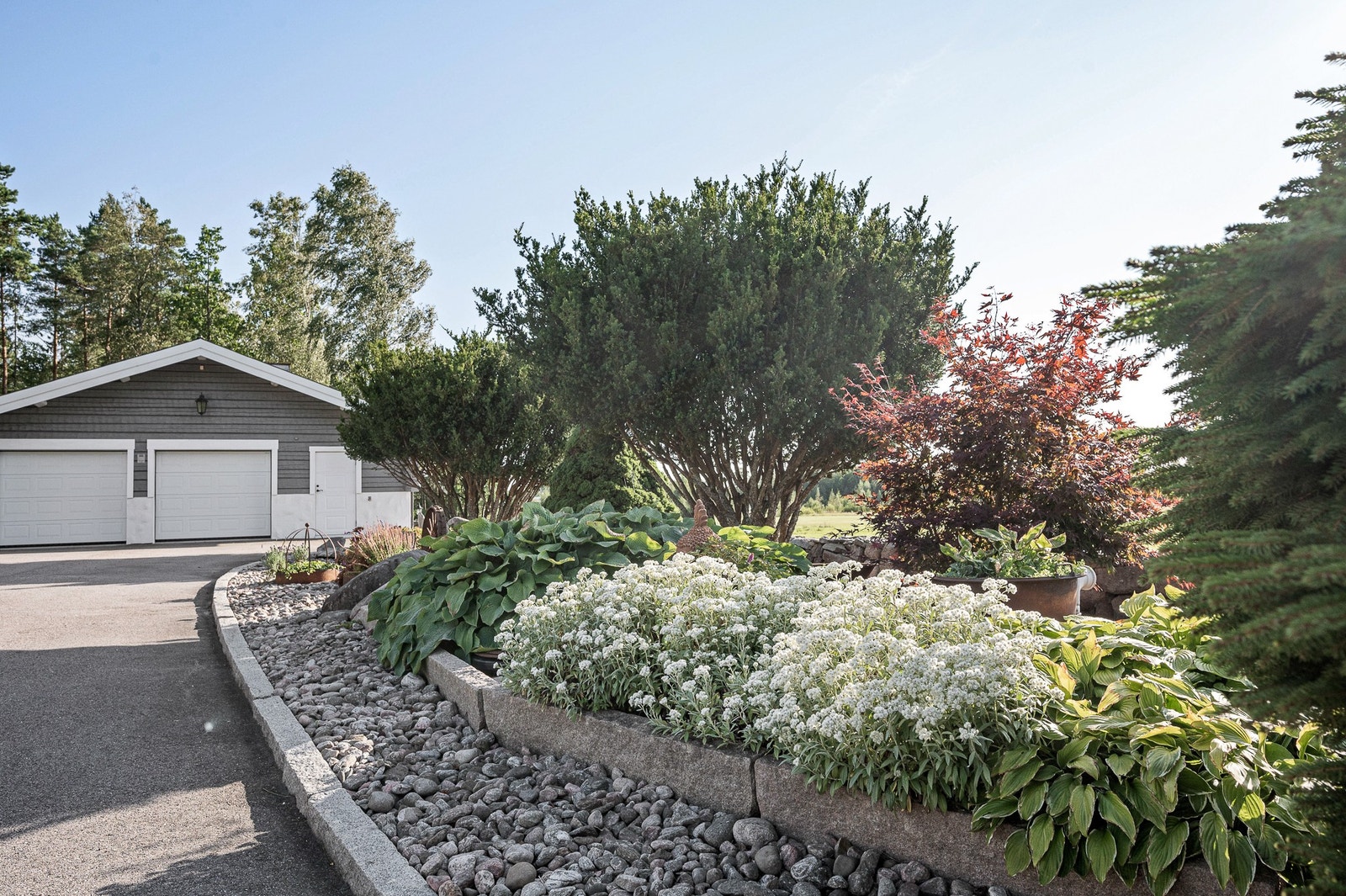 Vy mot garage och plantering vid den stiliga uppfarten Galleribilde