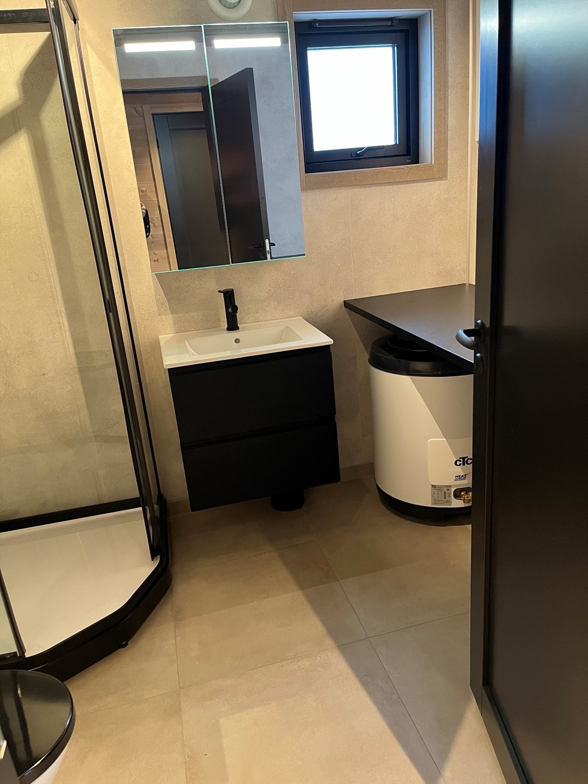 Hovedbadet med sorte detaljer. Wc, servant med skuffer, dusjkabinett. Opplegg vaskemaskin. Galleribilde