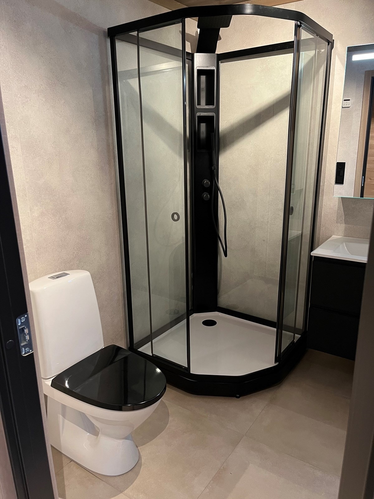 Hovedbadet med sorte detaljer. Wc, servant med skuffer, dusjkabinett. Opplegg vaskemaskin. Galleribilde