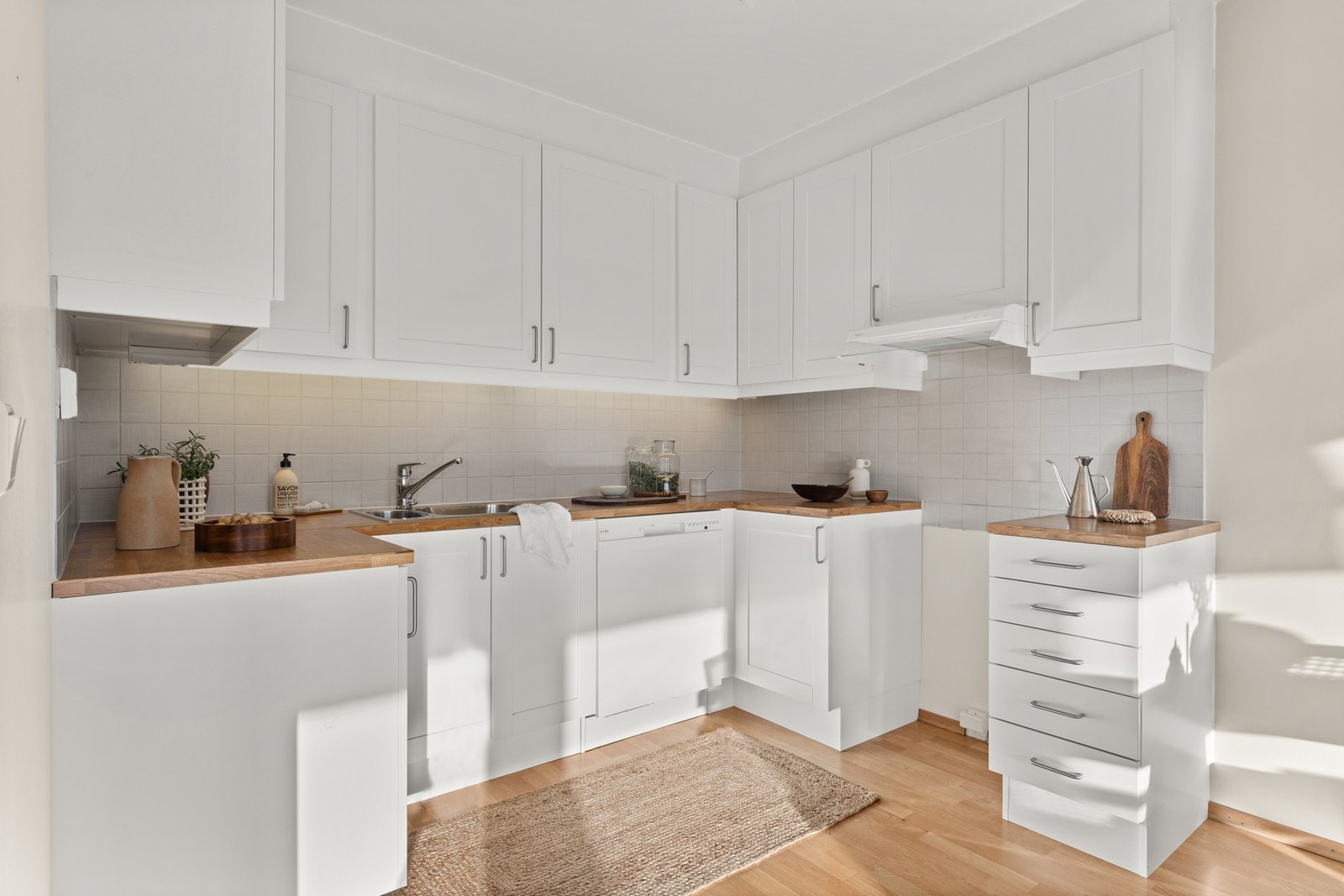 Innredningen er fra Sigdal og har hvite profilerte skap, laminat benkeplate og fliser over benkeplate Galleribilde