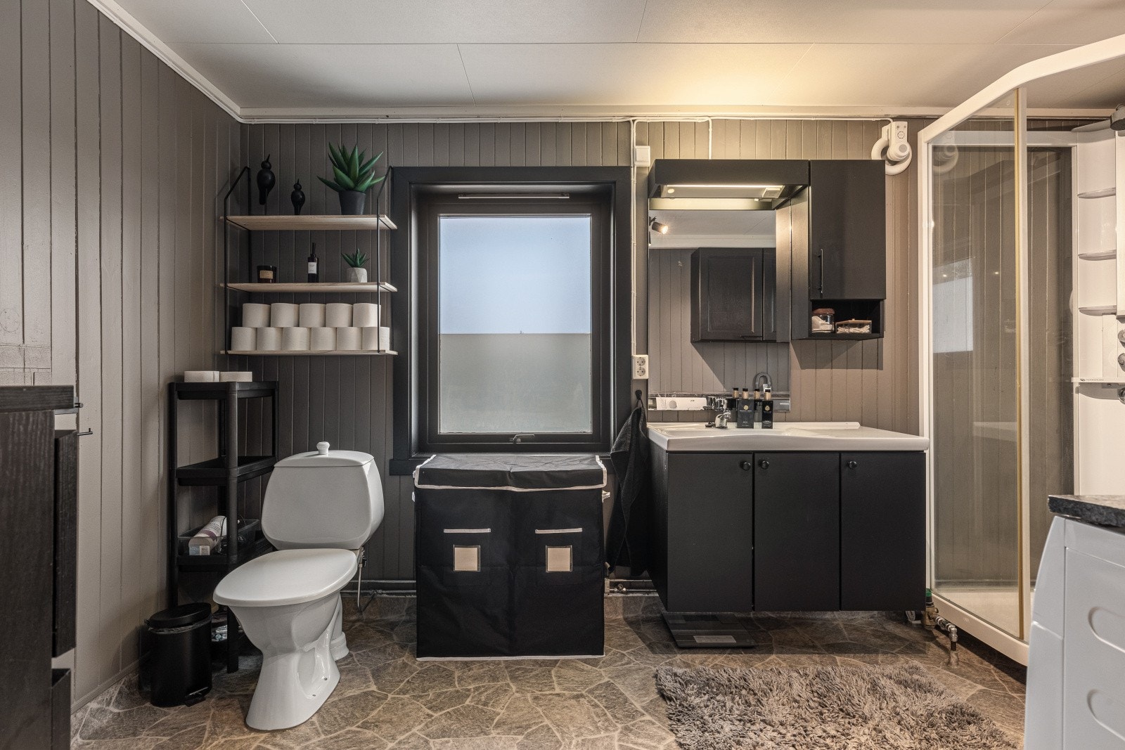 Baderommet er bestående av toalett, servant med underskap, dusjkabinett og opplegg for vaskemaskin Galleribilde