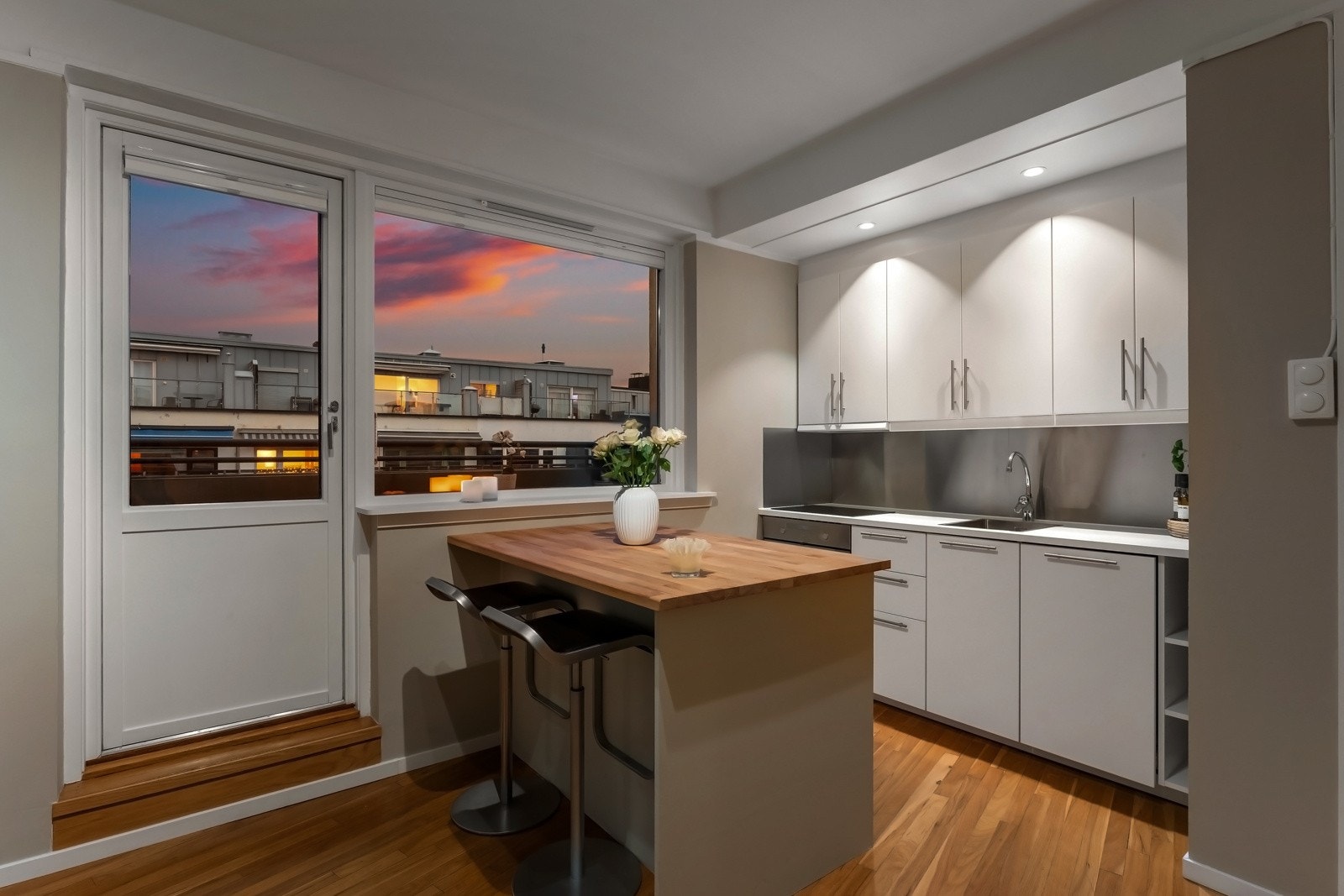 Den øvrige innredningen har hvite, glatte fronter og foliert, hvit benkeplate med nedfelt oppvaskkum av rustfritt stål. Galleribilde