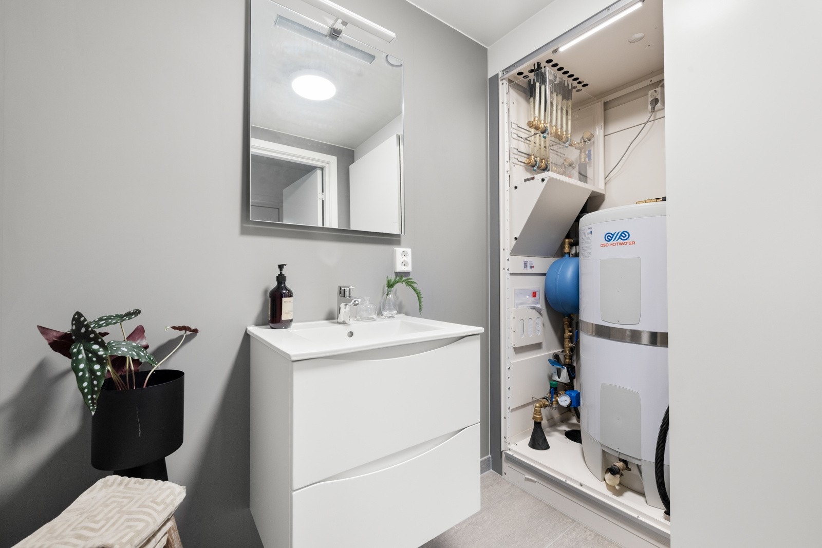 Innredningen består av stilrent servantmøblement, speil og vegghengt toalett med softclose sete. Det er satt inn en praktisk skyvedørsgarderobe som skjuler boligens varmtvannsbereder. NB! Bildene er hentet fra tilsvarende bolig i prosjektet. Galleribilde