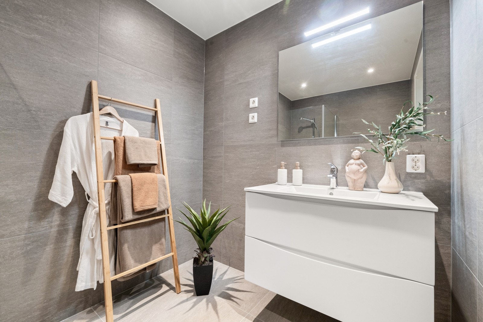 Smakfullt hovedbad med lysegrå storformatfliser på gulv og veggflater. Himlingen er lyssatt med LED downlights. NB! Bildene er hentet fra tilsvarende bolig i prosjektet. Galleribilde