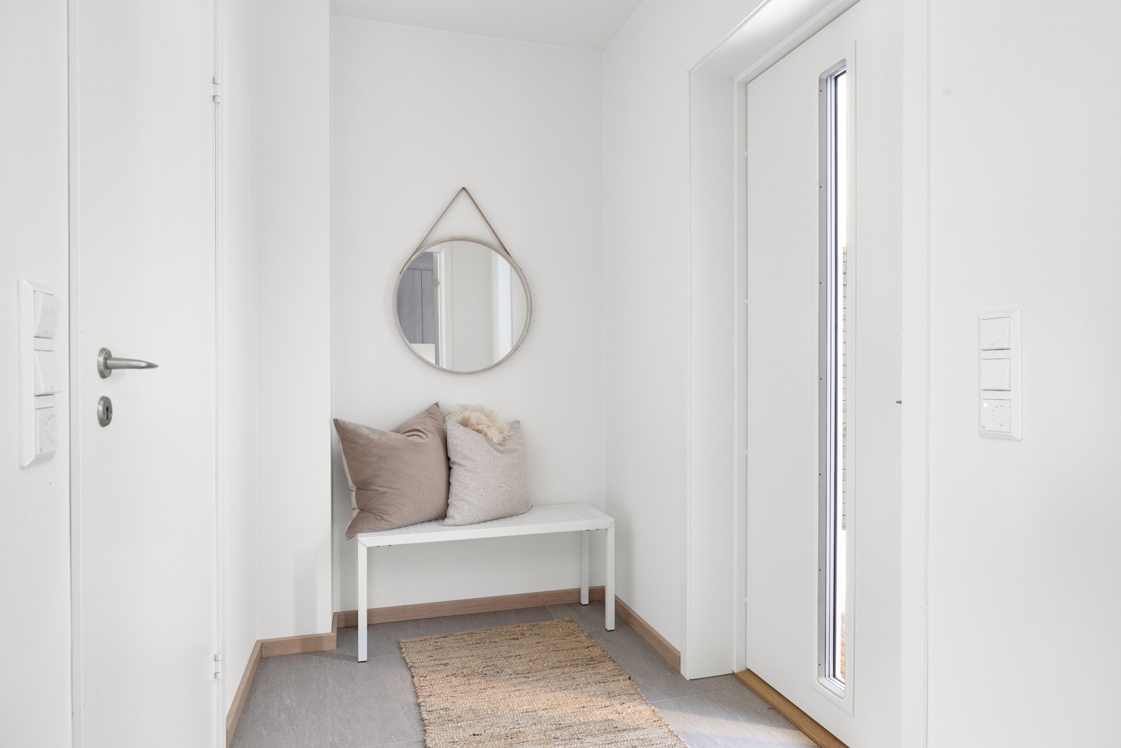 Lys og innbydende entre med delikate storformatfliser på gulv med herlig underliggende gulvvarme og lysmalte slette overflater. Det er god plass til å sette inn ønsket garderobeløsning. NB! Bildene er hentet fra tilsvarende bolig i prosjektet. Galleribilde