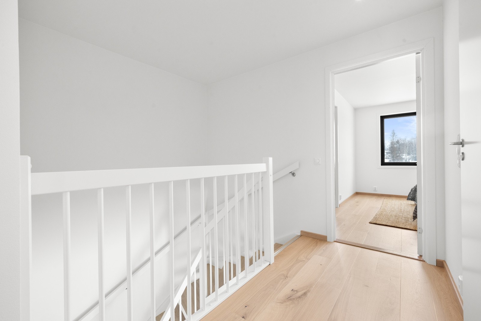 En flott hvitmalt heltre trapp med trinn i lys eik fører enkelt opp til boligens hovedbad og soveromsavdeling i 2.etasje. Himlingen er pent lyssatt med LED downlights. NB! Bildene er hentet fra tilsvarende bolig i prosjektet. Galleribilde