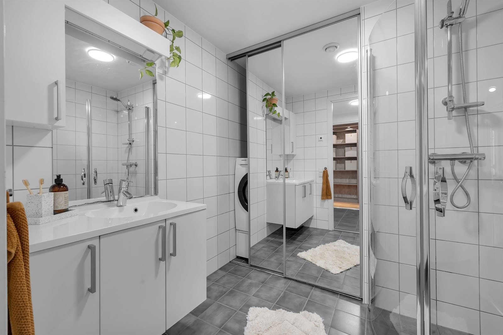 Pent flislagt bad med vaskenisje bak skyvedørsgarderobe med speilfronter Galleribilde