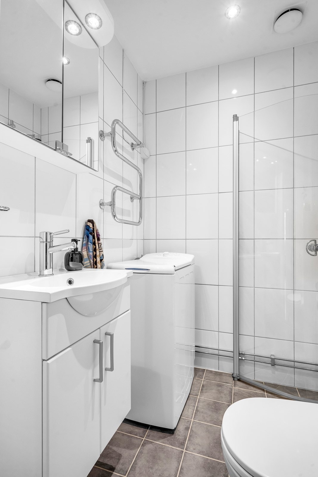 Innredning med vegghengt klosett, servantinnredning, servant med ettgreps blandebatteri, dusjdører og dusjarmatur. Galleribilde