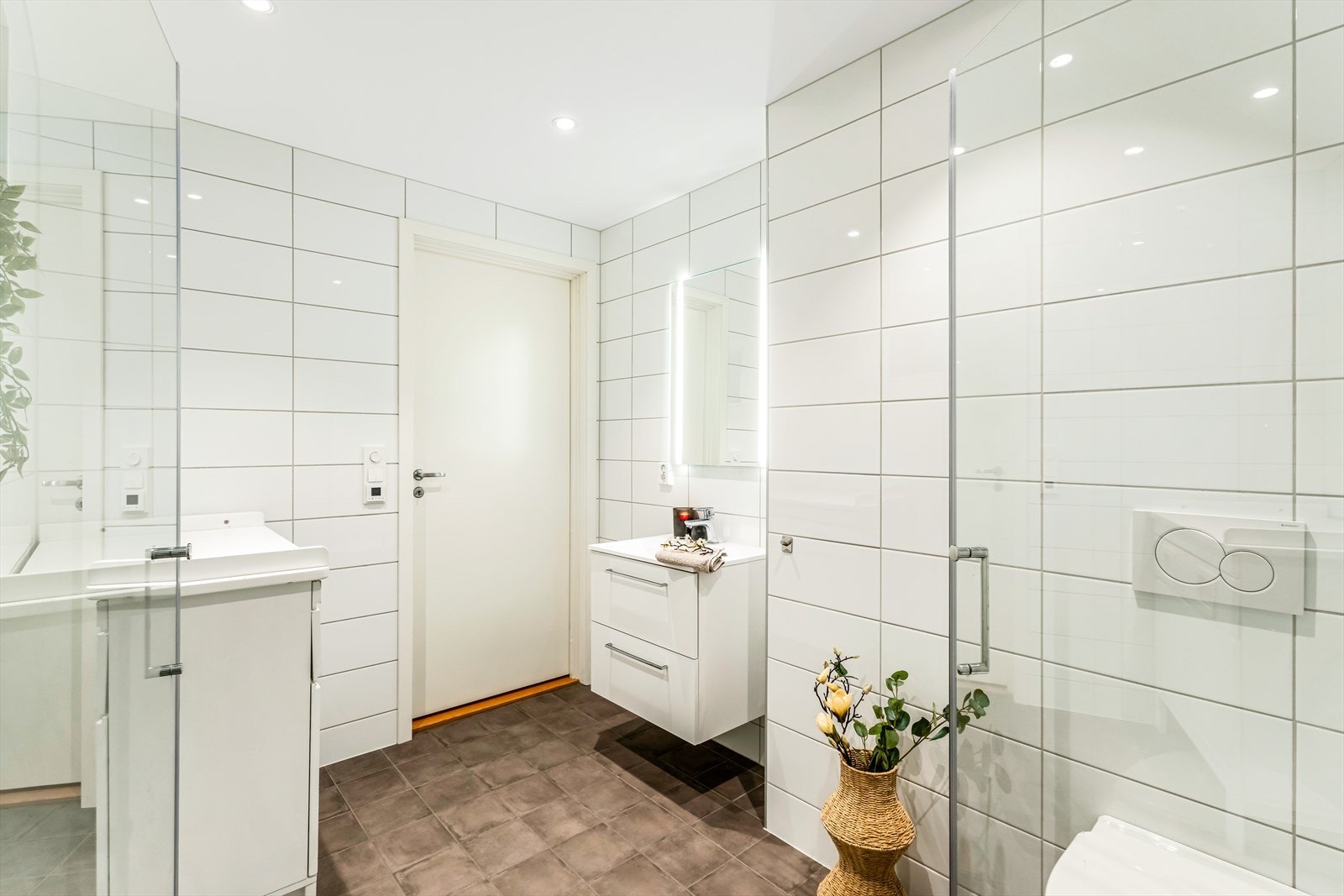 Det har downlights i himlingen og er utstyrt med vegghengt toalett, baderomsinnredning med servant, belyst speil og dusj. Galleribilde