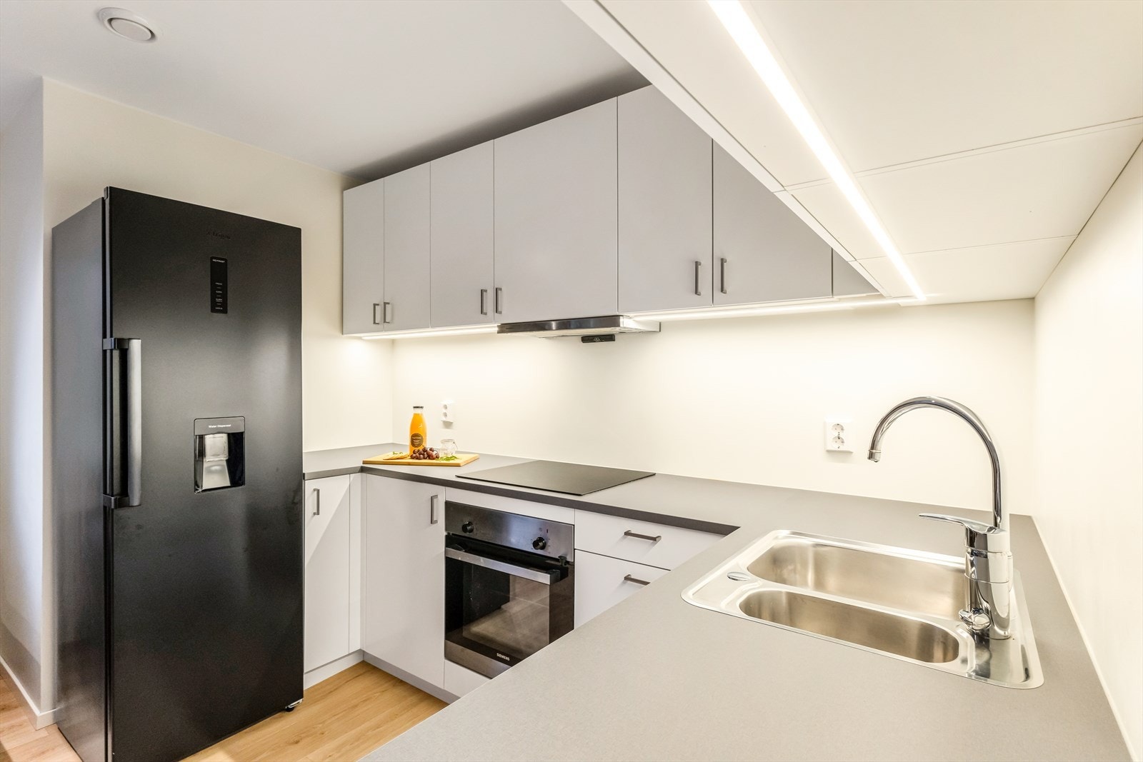 Kjøkkeninnredningen fra Drømmekjøkkenet har en stilren utførelse med hvite, glatte fronter og laminert benkeplate. Galleribilde