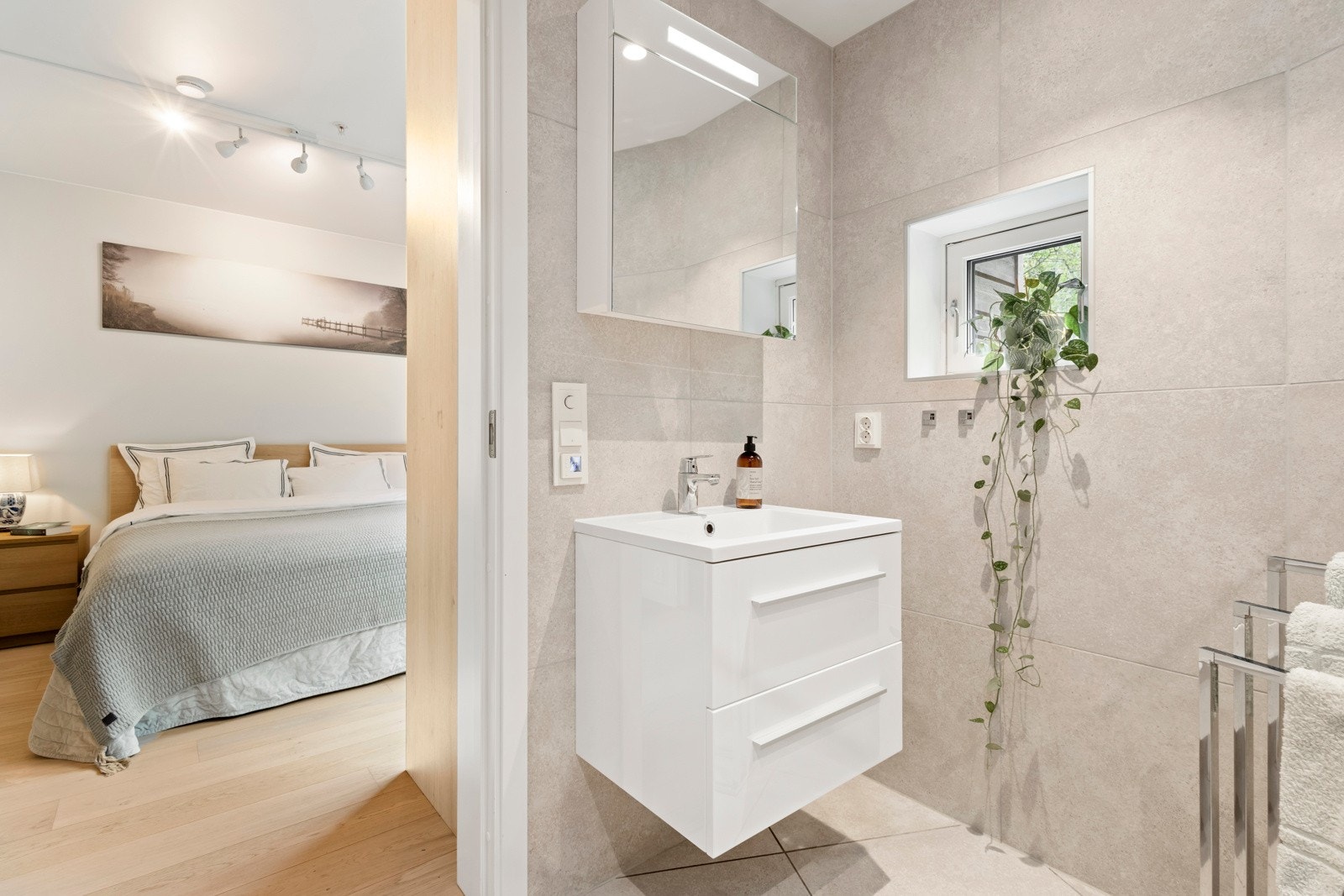 Lyst, delikat baderom innredet med dusjnisje, servant med skuffeseksjon og klosett. Galleribilde