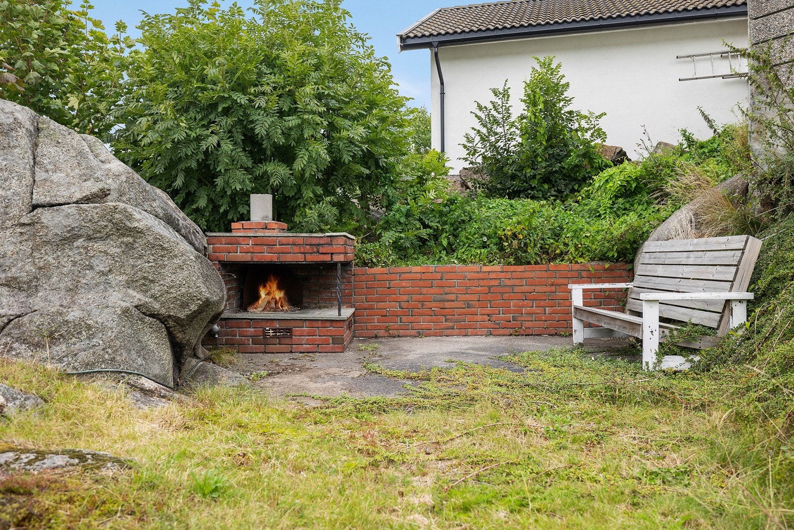 Litt opp i terrenget fra terrassen er det en skjermet platting med plassbygd, åpen utepeis. Galleribilde