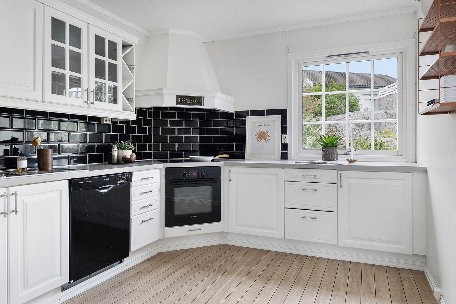 Kjøkkeninnredningen har vitrineskap, lyse, profilerte fronter og laminert benkeplate med nedfelt oppvaskkum. Det er fliser på veggen mellom benk. Hvitevarene består av stekeovn, induksjonstopp og oppvaskmaskin, og det er også plass til kjøle/fryseskap. Galleribilde