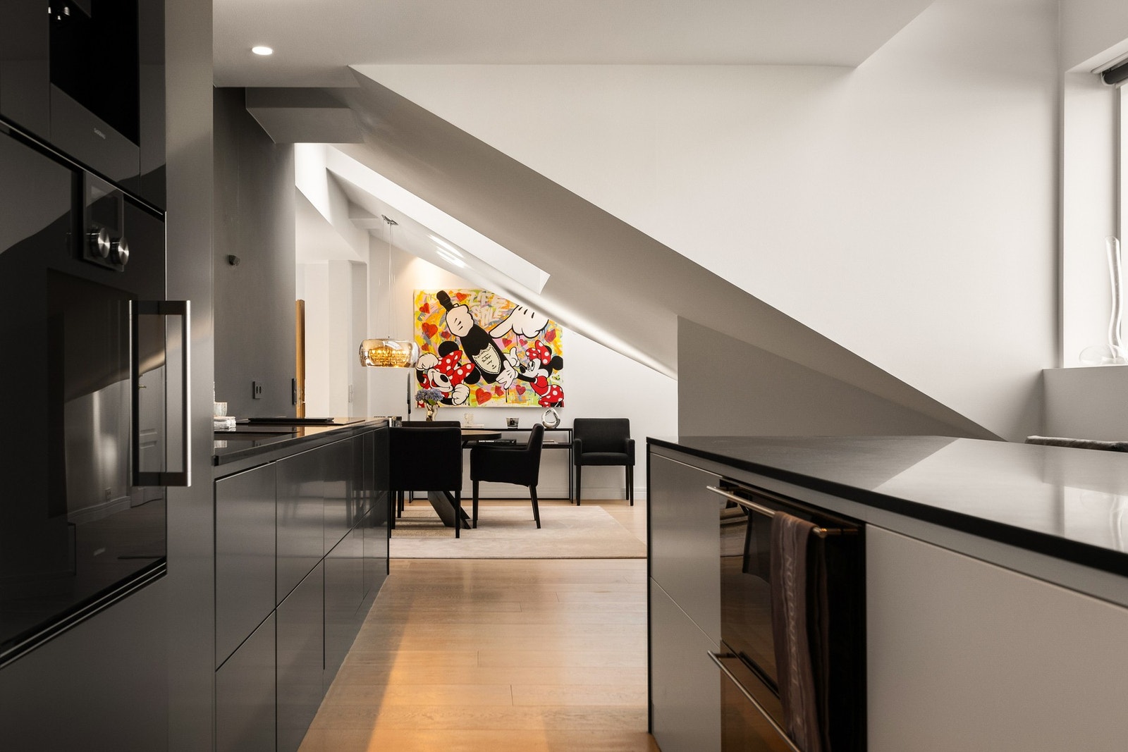 Kjøkkenet er innredet med stilrene, slette fronter og en benkeplate i stein. Galleribilde