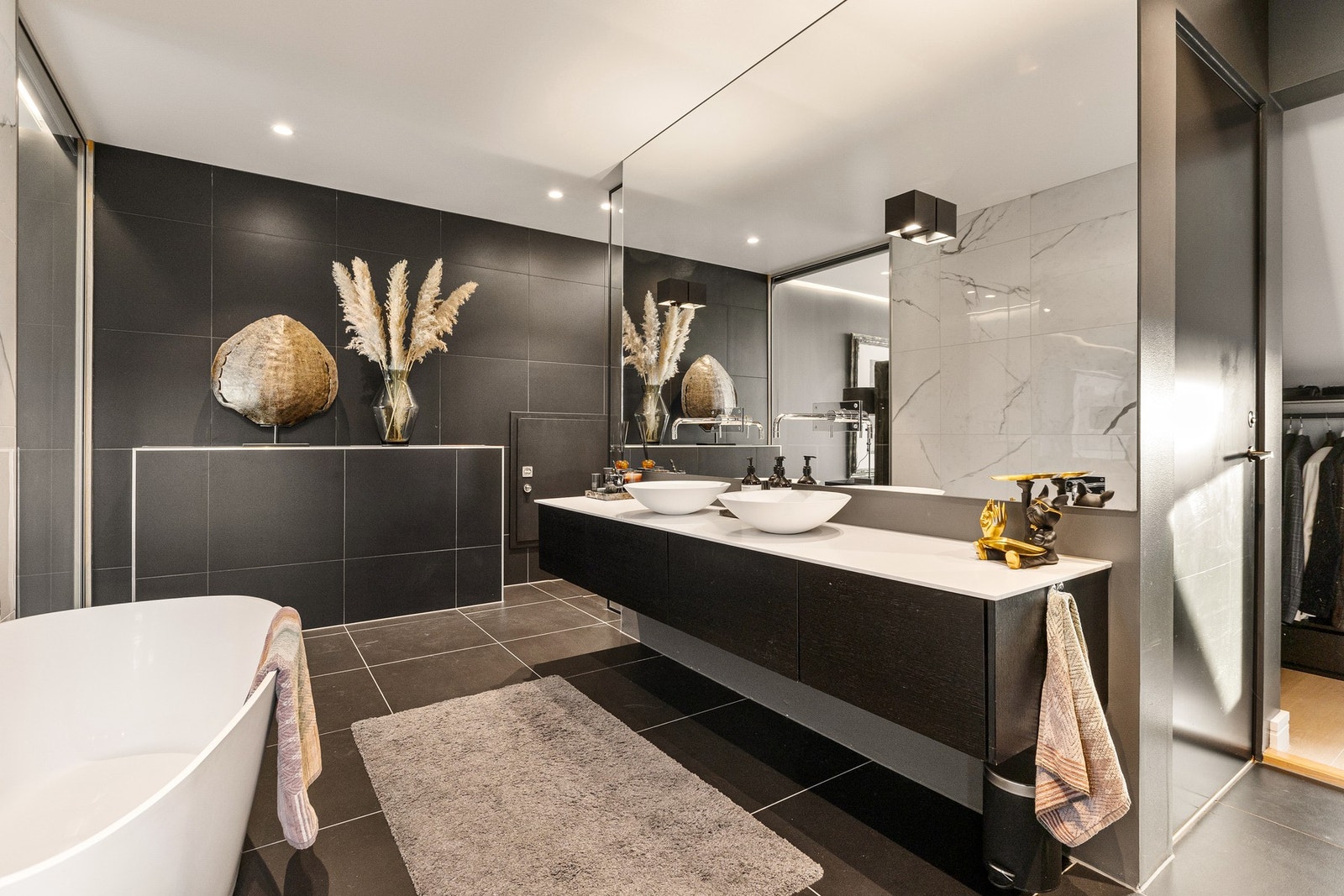 Hovedbadet har et stilrent uttrykk med flislagt gulv og behagelig gulvvarme, malte veggflater og en nedsenket himling med integrerte downlights for stemningsfull belysning. Galleribilde