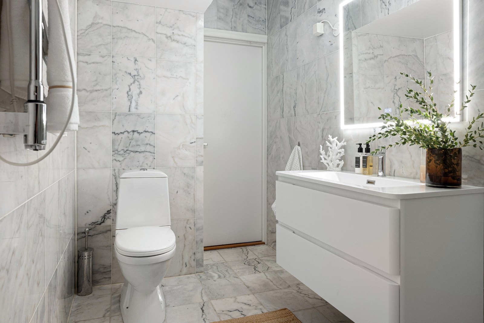 Videre har badet et gulvstående klosett, veggmontert elektrisk håndkletørker og opplegg for vaskemaskin. Galleribilde