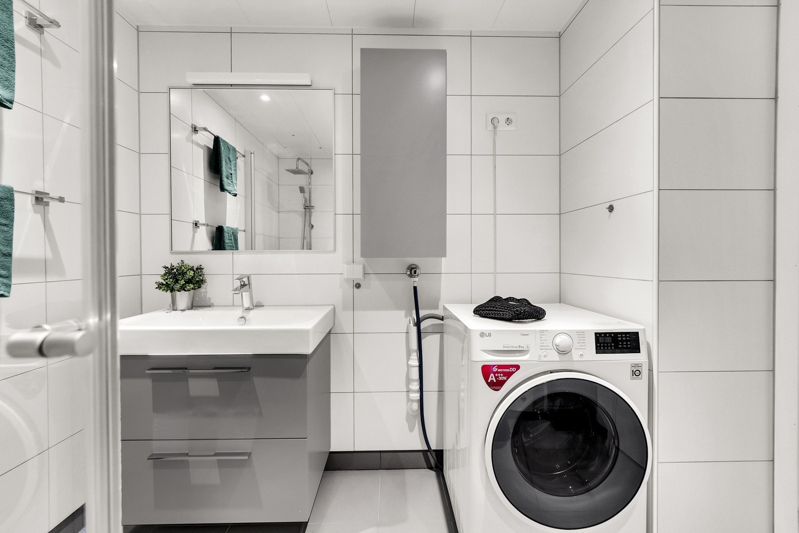 Baderomsinnredning bestående av servant med skuffeseksjon, dusjhjørne, toalett og opplegg for vaskemaskin. Galleribilde