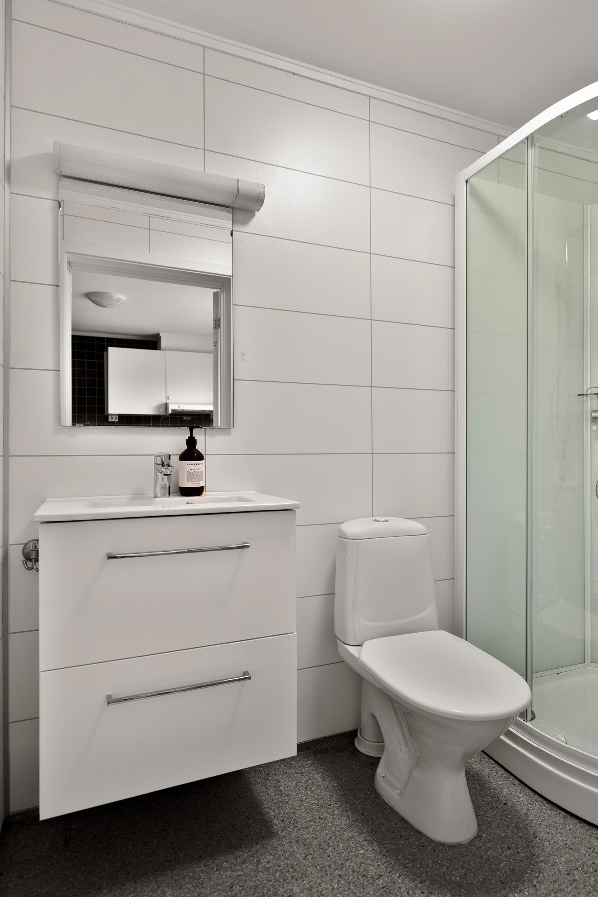 Baderommet har toalett, innredning med oppbevaringsplass i skuffer, dusjkabinett og opplegg for vaskemaskin. Galleribilde