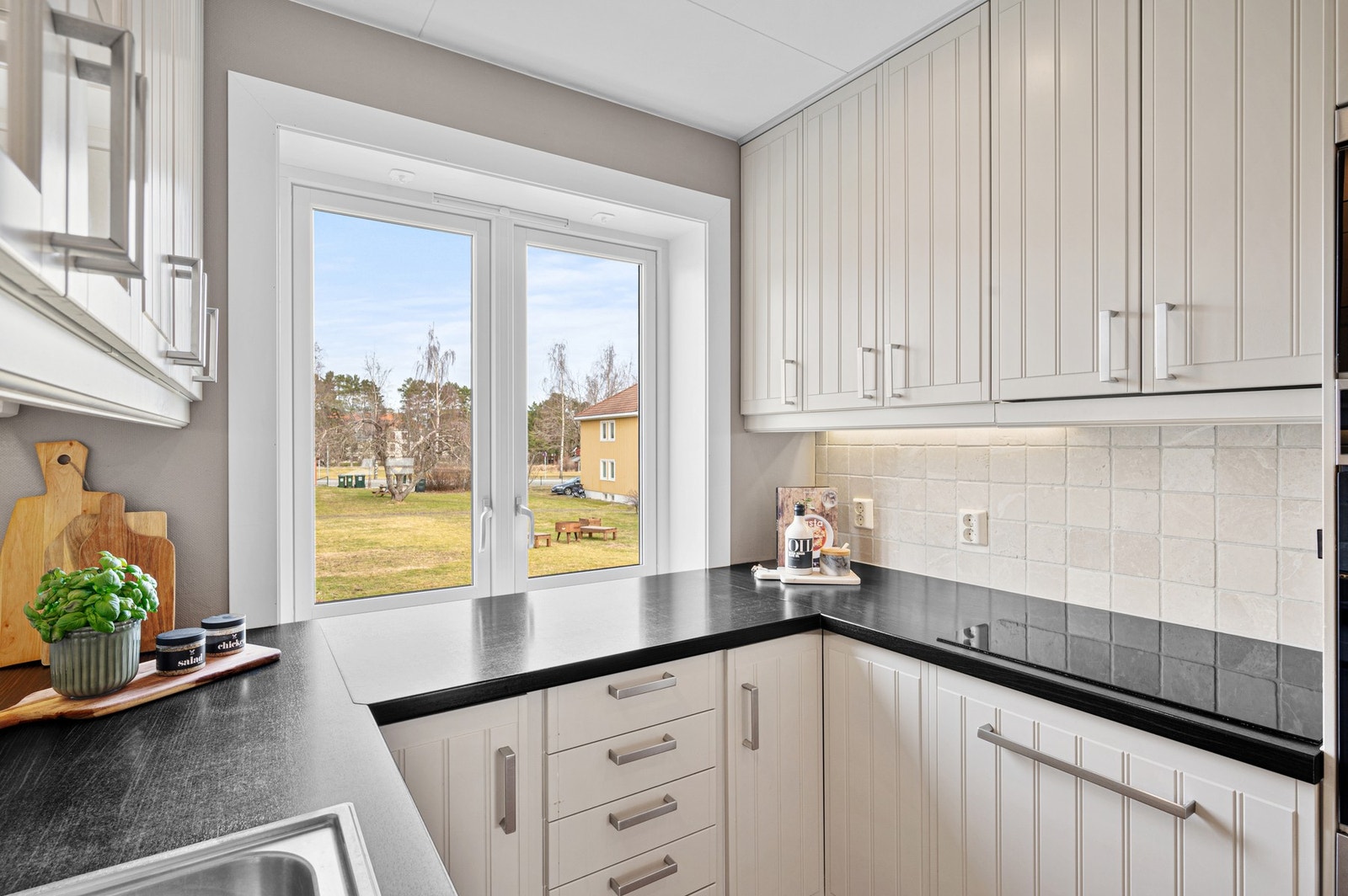 Fra kjøkkenvinduet har man utsikt til borettslagets fellesareal med store grøntområder og benker. Galleribilde