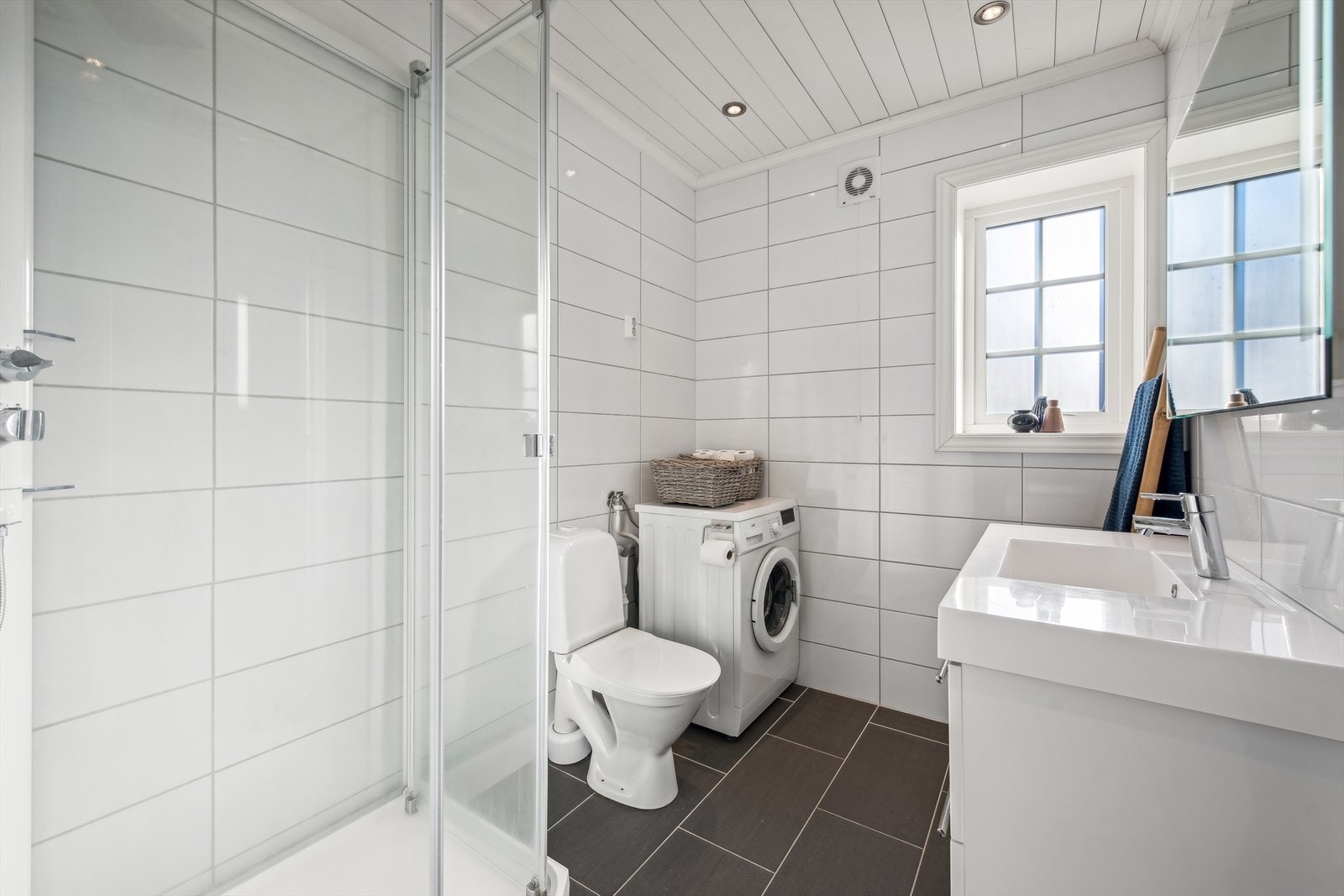 Badet i første etasje er praktisk innredet med dusjkabinett og har et moderne uttrykk. Baderomsinnredningen inkluderer en toppmontert servant, speil med integrert belysning, og et gulvmontert toalett. Opplegg for vaskemaskin. Galleribilde