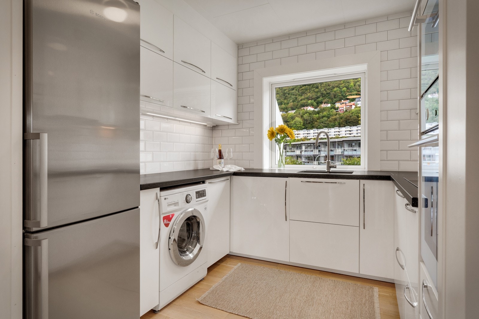 Pen, tidløs kjøkkeninnredning med hvite, slette fronter og benkeplate i laminat. Galleribilde