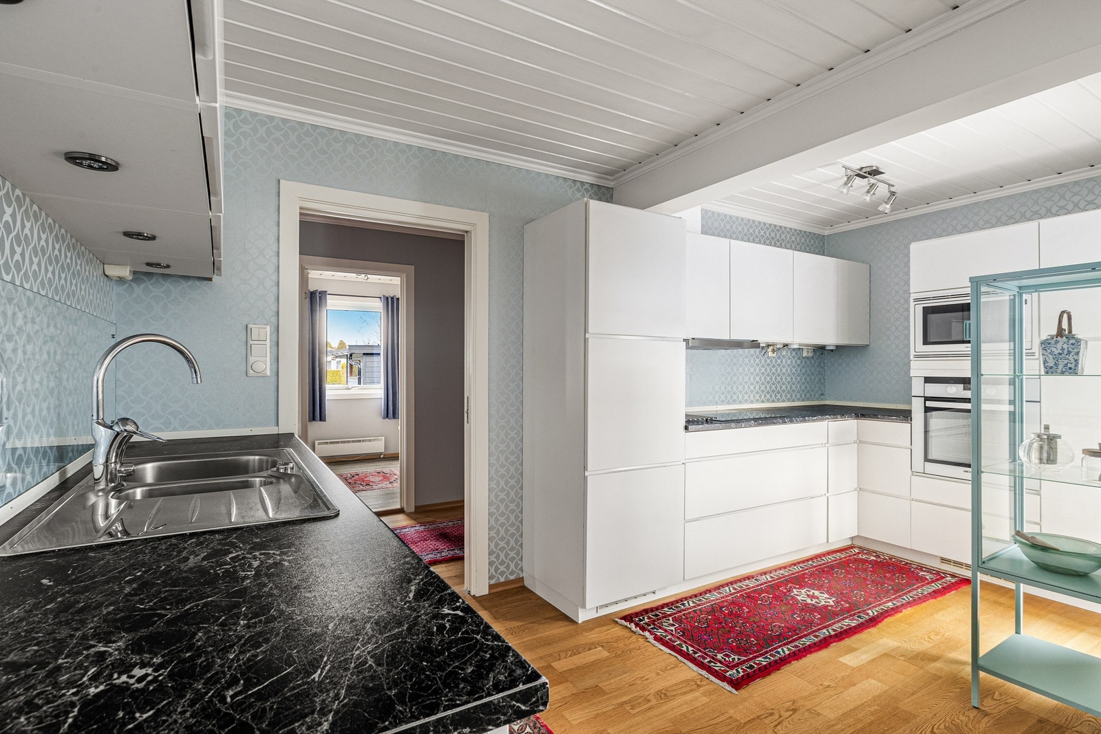 Mellom benken og overskapene er det herdet glassplate som beskytter tapeten mot sprut. Innredningen har en matt, men samtidig glatt overflate som er lett å holde ren. Galleribilde