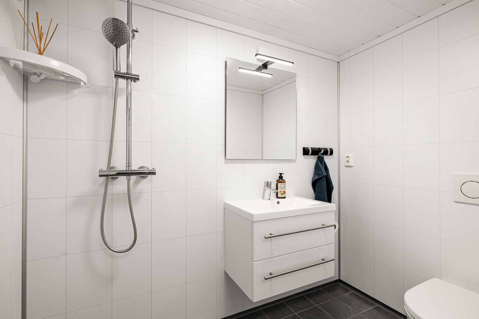 Badet i underetasjen med flislagt gulv, wc, servant og dusjhjørne. Galleribilde