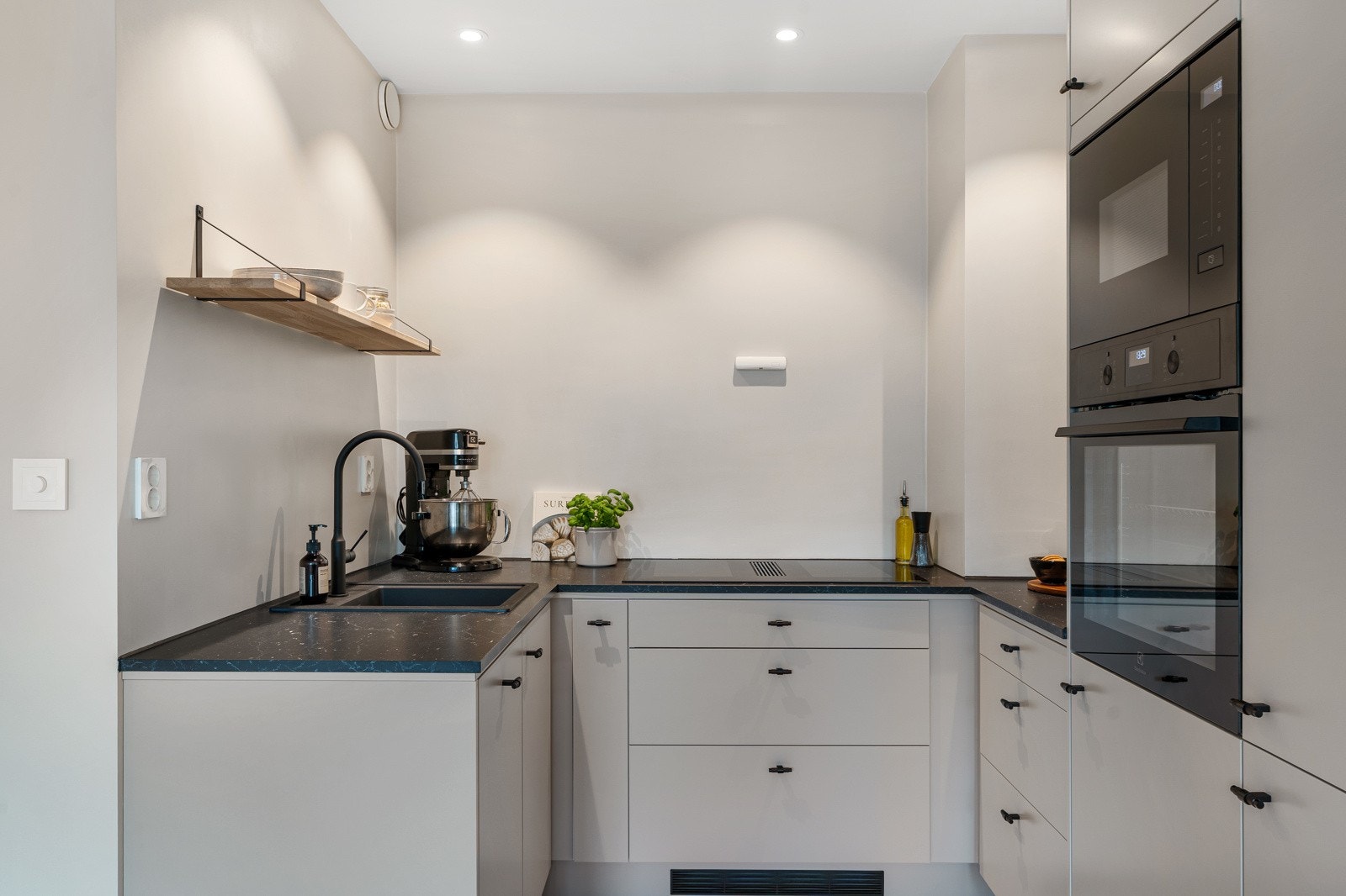 Innredningen er tidløs med minimalistiske fronter i fargen kalkstein og en lekker mørk benkeplate. Galleribilde