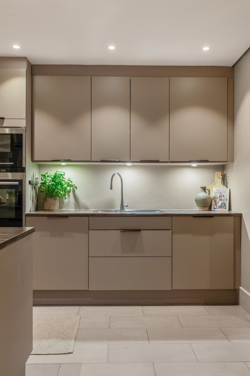 Medfølgende, integrerte hvitevarer bestående av oppvaskmaskin, stekeovn med nedfelt induksjonstopp, mikrobølgeovn, kjøleskap og fryseskap i kjøkkenøy. Galleribilde