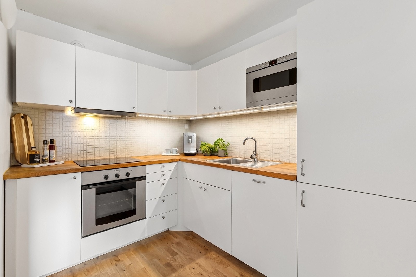 Kjøkkeninnredning fra 2013 med hvite fronter, heltre benkeplate og flislagt backsplash. Ventilator med kullfilter Galleribilde