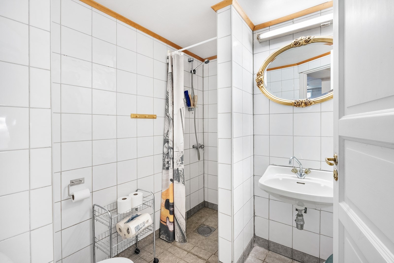 Badet i kjelleren har flislagte overflater og elektriske varmekabler - Rommet har servant, toalett og egen dusjnisje Galleribilde