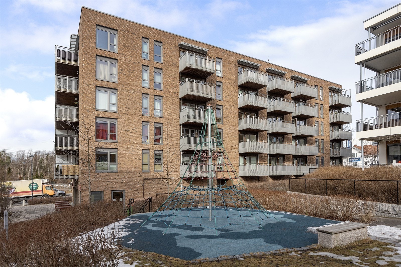 Skjermet og bilfritt indre gårdsrom pent opparbeidet med gressplen, heller, prydbusker, hekker, trær, sykkelstativ, lekeapparater, benker, bord, belegningsstein og støpte gangveier Galleribilde