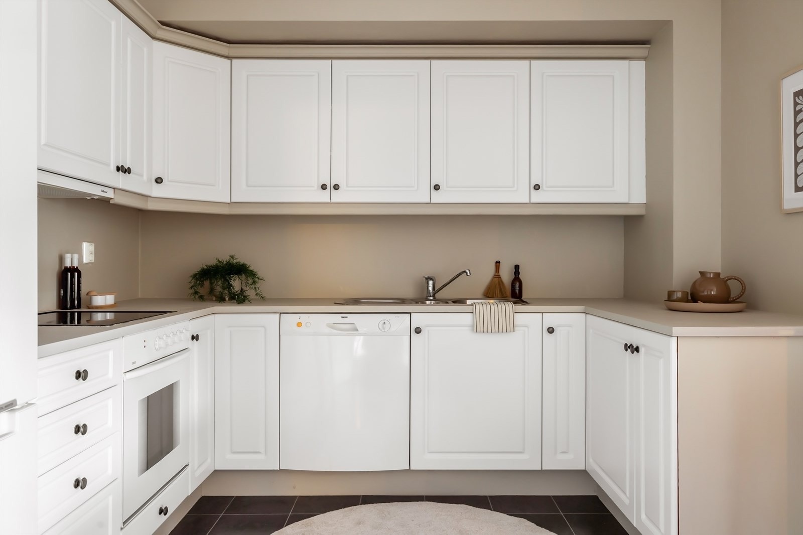 Hvit kjøkkeninnredning med mye skap- og benkeplass. Galleribilde