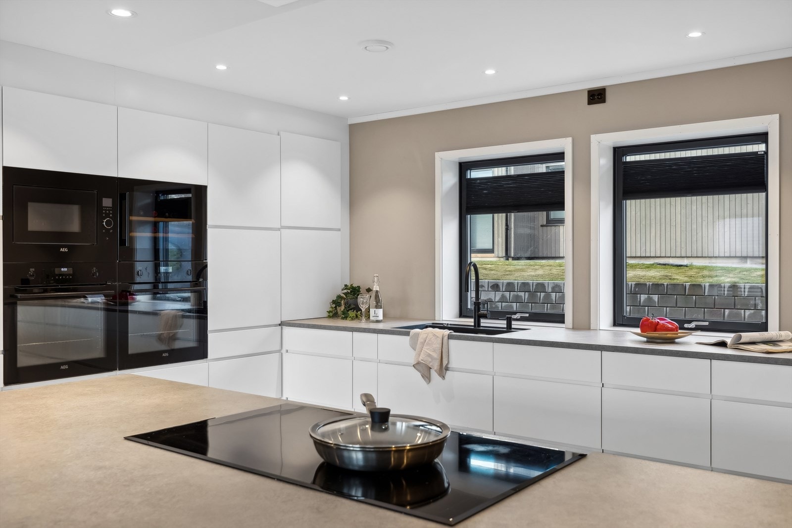 Stilrent kjøkken som er utstyrt med platetopp, to stekeovner, mikrobølgeovn, vinskap, kjøleskap, fryseskap og oppvaskmaskin. Galleribilde