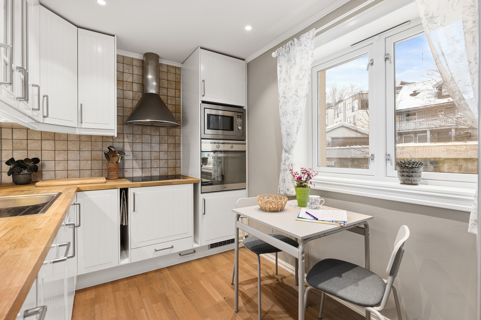 Kjøkken i separat løsning med plass til spisebord. Kjøkkenet har parkett på gulv og downlights i himling Galleribilde