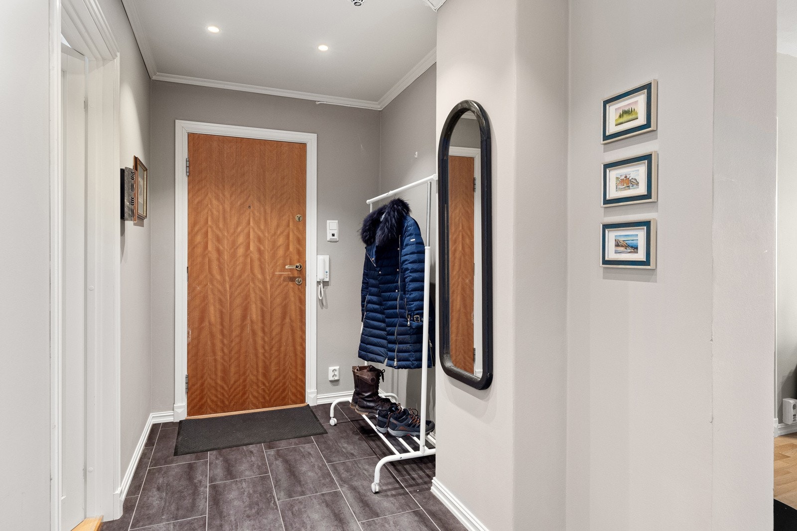 Lys og innbydende entré med fliser på gulv med varme, malte overflater og downlights i himling. Galleribilde