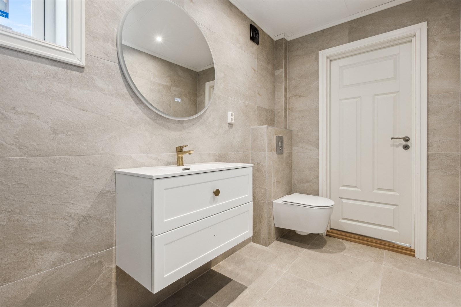 Hovedbadet er beliggende i første etasje, er med fliselagte overflater på vegger og gulv. Videre er rommet utstyrt med baderomsinnredning med nedfelt servant, vegghengt speil og vegghengt toalett. Et pent baderom! Galleribilde