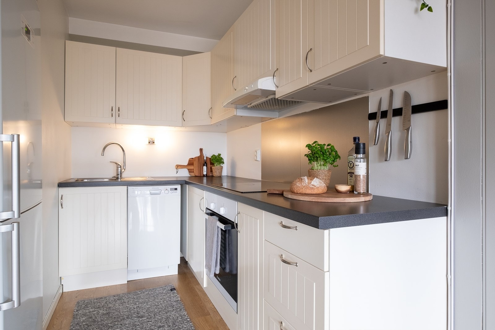 Kjøkkenet er i delvis åpen løsning mot stuen og er innredet med profilerte fronter, laminat benkeplate, metallvask med ett-greps blandebatteri og stålplate mellom benkeplate og overskap Galleribilde