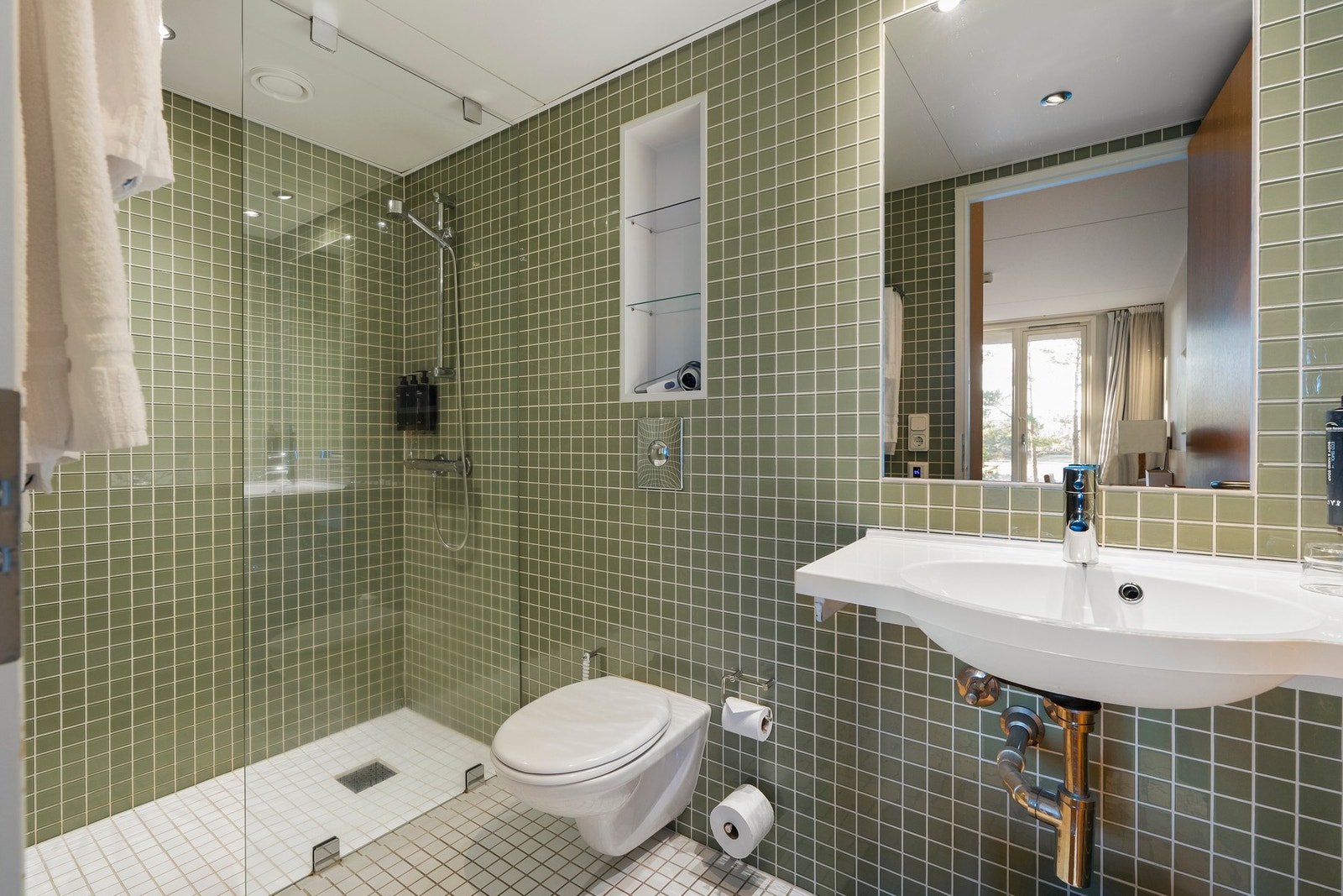 Flislagt bad med varmekabler, lyst og moderne med downlights i taket, baderomsinnredning fra Grohe med speil innfelt i flisvegg. Galleribilde