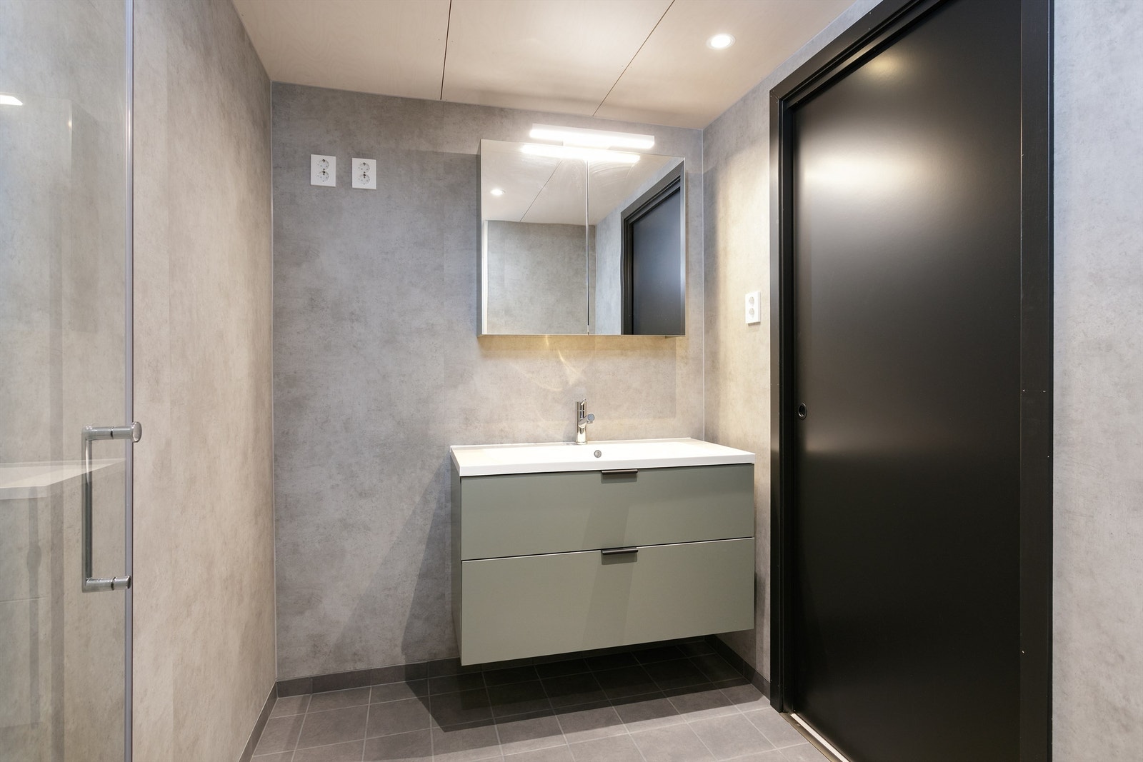 Bad med flislagt gulv, baderomsplater på vegger og himlinger i x-finer. Speilskap med overlys over servant. Galleribilde