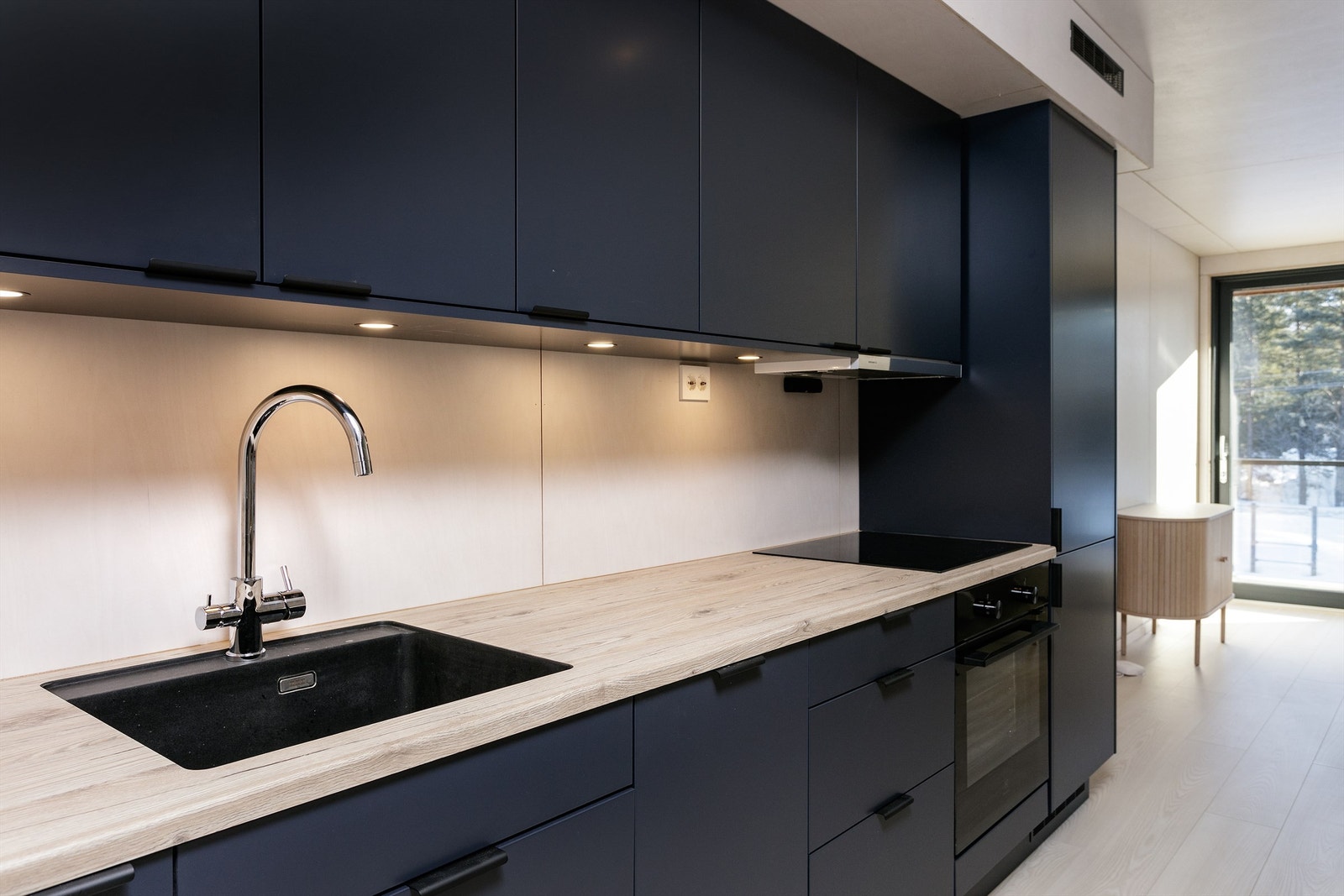 Kjøkkenet har sort innredning med glatte fronter og benkeplate av laminat med nedfelt oppvaskkum. Kjøl/fryseskap, oppvaskmaskin, platetopp, stekeovn, vannstoppsystem og komfyrvakt. Kjøkkenventilator med avtrekk ut. Galleribilde