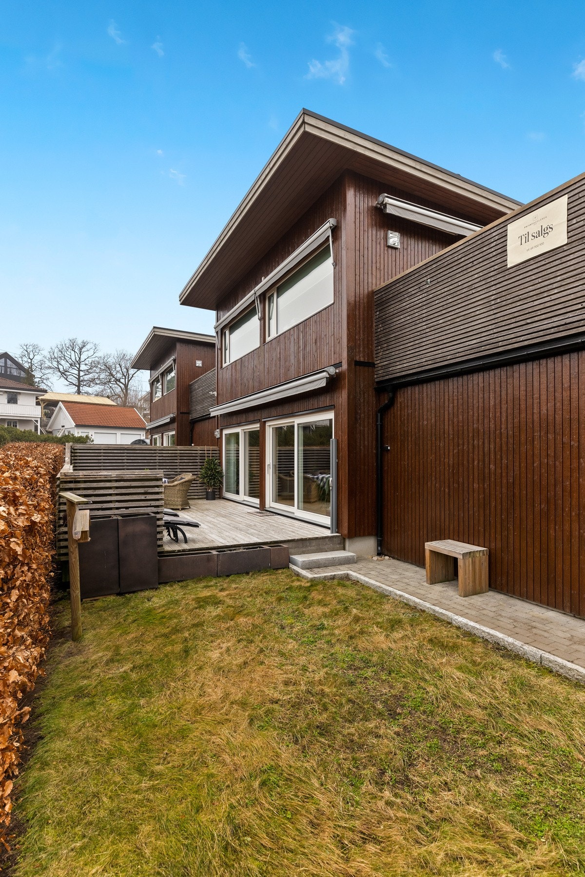 Hekk i tomtens lengde utenfor terrassen mot vest gjør at uteområdet er skjermet mot innsyn hele året. Galleribilde