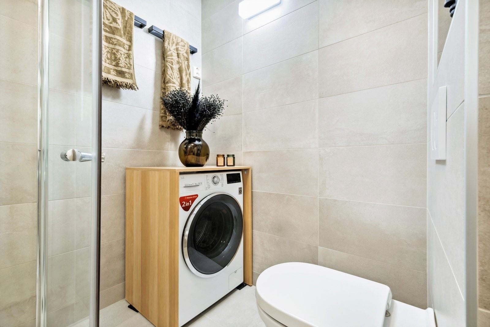 Dusjvegger av glass, vegghengt wc, innredning med servant, opplegg for vaskemaskin. Galleribilde